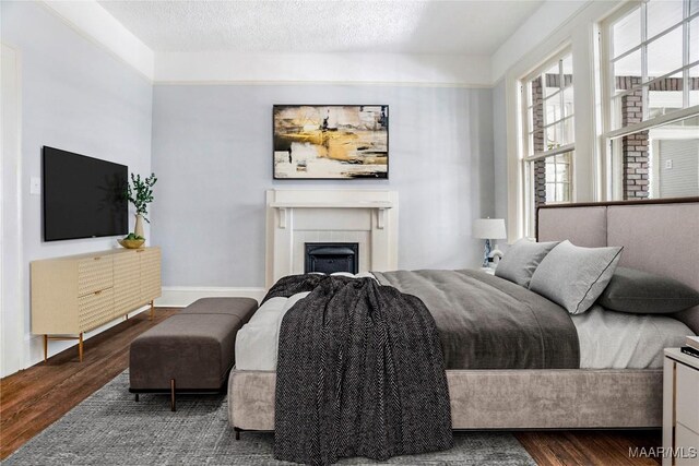1427 S Court St, Montgomery, AL 36104 - bedroom with wood finished floors, a fireplace, and a textured ceiling