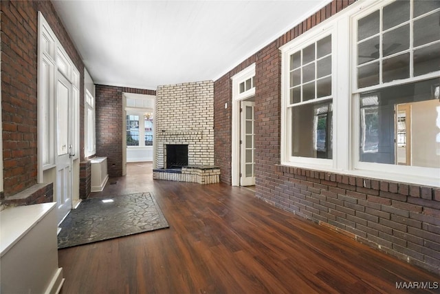 1427 S Court St, Montgomery, AL 36104 - unfurnished living room with brick wall, wood finished floors, and a fireplace