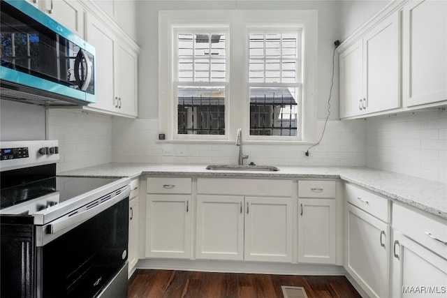 kitchen with light stone countertops, sink, dark hardwood / wood-style floors, white cabinets, and appliances with stainless steel finishes