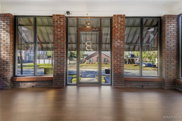 doorway featuring a wealth of natural light, dark wood-type flooring, and brick wall