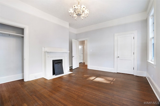 unfurnished living room featuring a notable chandelier and dark hardwood / wood-style flooring