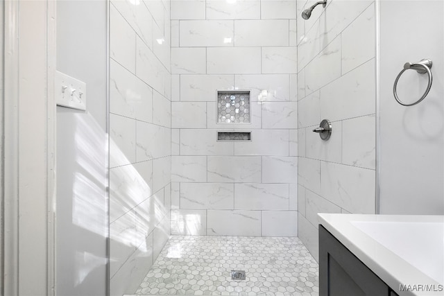 bathroom with a tile shower and vanity