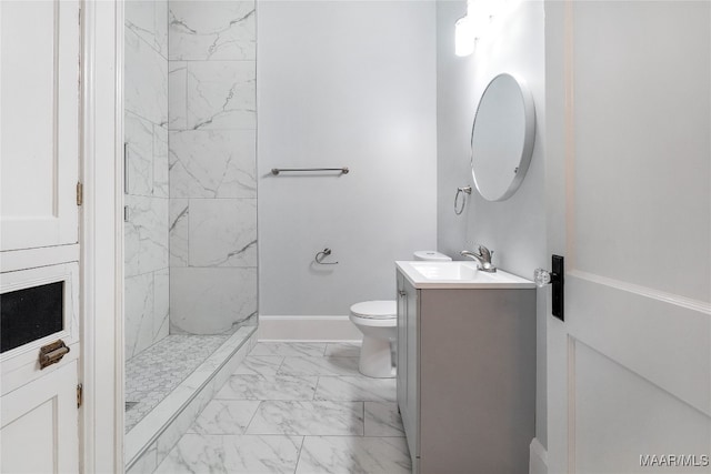 bathroom featuring a tile shower, vanity, and toilet