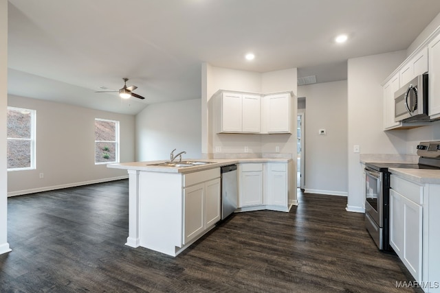 kitchen with kitchen peninsula, appliances with stainless steel finishes, dark hardwood / wood-style flooring, sink, and white cabinets