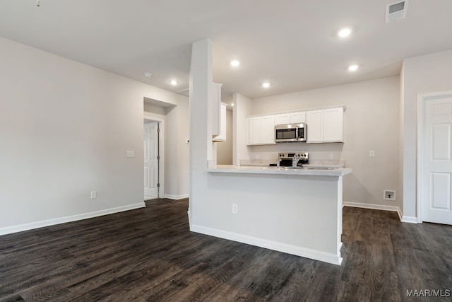 kitchen with white cabinets, appliances with stainless steel finishes, dark hardwood / wood-style flooring, and kitchen peninsula