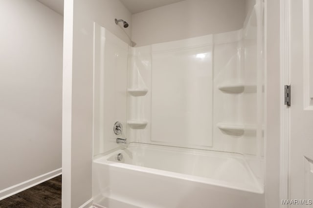 bathroom with hardwood / wood-style flooring and washtub / shower combination