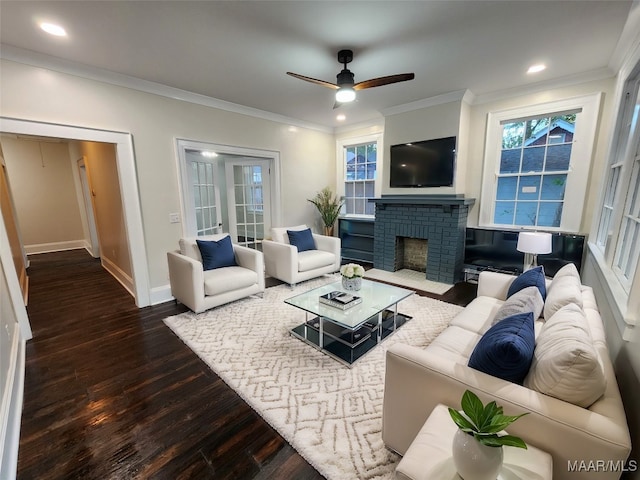 living room featuring a fireplace, ceiling fan, crown molding, and dark wood-type flooring