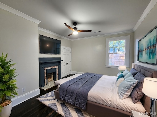 bedroom featuring dark hardwood / wood-style flooring, a stone fireplace, ceiling fan, and ornamental molding