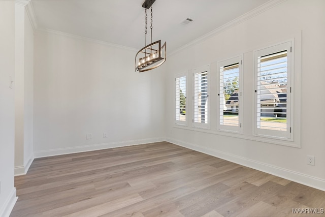 empty room featuring a chandelier, light hardwood / wood-style floors, and ornamental molding