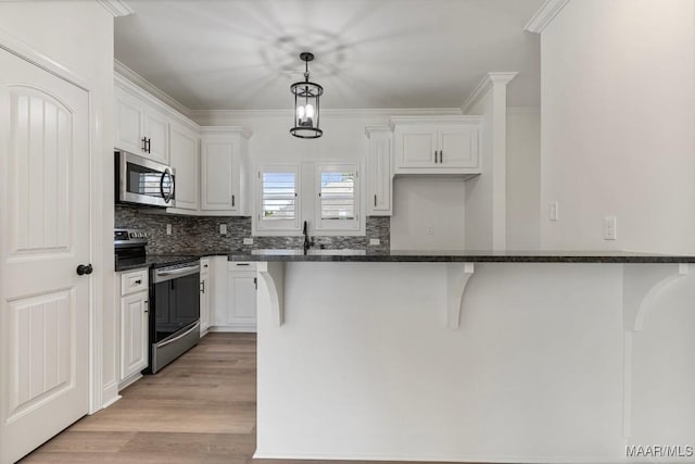 2524 Crenshaw Close Ct S, Montgomery, AL 36106 - kitchen featuring stainless steel appliances, white cabinets, backsplash, a breakfast bar area, and light wood-style floors