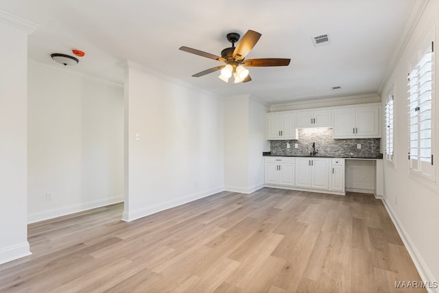 kitchen with white cabinets, light wood-type flooring, and ornamental molding