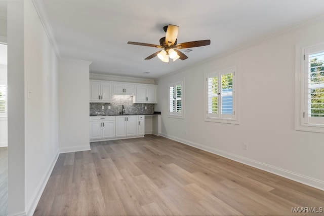 kitchen with white cabinetry, crown molding, sink, and light wood-type flooring