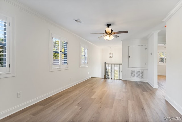 empty room featuring ornamental molding, light wood-type flooring, ceiling fan, and a healthy amount of sunlight