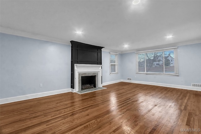 unfurnished living room featuring hardwood / wood-style flooring, crown molding, and a premium fireplace