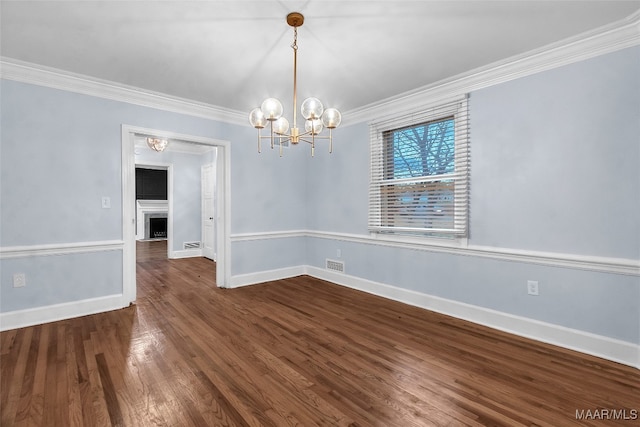 empty room featuring crown molding, dark hardwood / wood-style flooring, and a notable chandelier