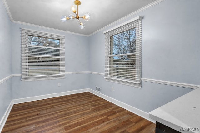 spare room featuring crown molding, plenty of natural light, dark wood-type flooring, and a notable chandelier