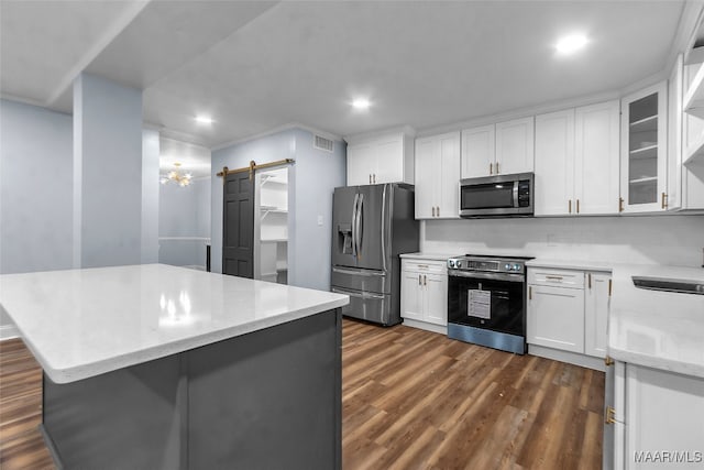 kitchen featuring stainless steel appliances, a barn door, dark hardwood / wood-style flooring, decorative backsplash, and white cabinets