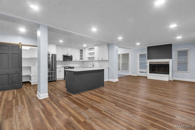 kitchen featuring appliances with stainless steel finishes, a fireplace, dark wood-type flooring, sink, and white cabinets