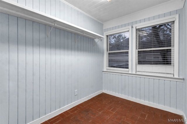 empty room with crown molding and wooden walls