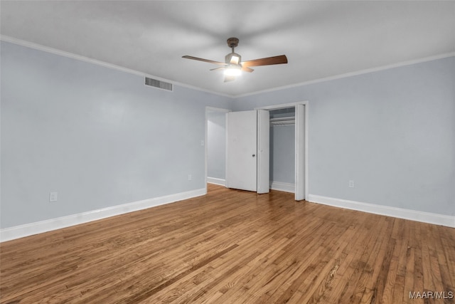 unfurnished bedroom featuring ceiling fan, light wood-type flooring, crown molding, and a closet