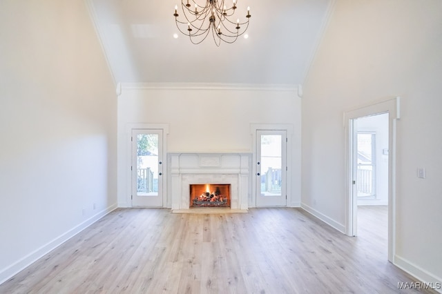 unfurnished living room featuring crown molding, a high end fireplace, an inviting chandelier, and light wood-type flooring