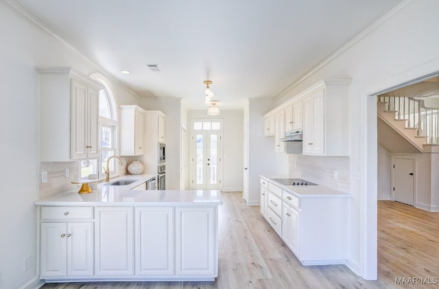 kitchen featuring white cabinetry, sink, black electric stovetop, crown molding, and light wood-type flooring