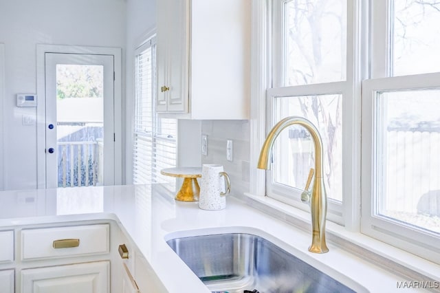 interior details featuring white cabinetry, sink, and backsplash