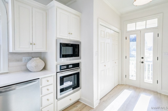 kitchen with french doors, white cabinetry, stainless steel appliances, and backsplash