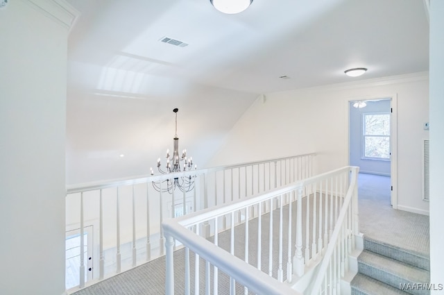 hallway with an inviting chandelier, ornamental molding, vaulted ceiling, and light carpet