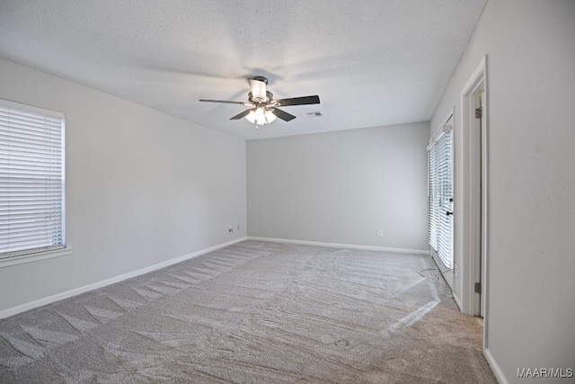 carpeted empty room with ceiling fan, a textured ceiling, and a wealth of natural light