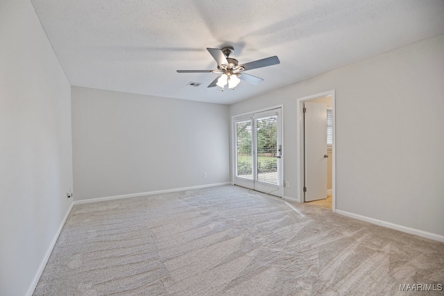 spare room with a textured ceiling, ceiling fan, and light carpet