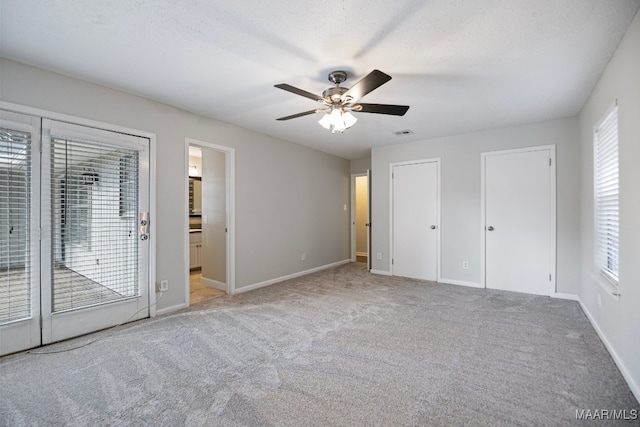 unfurnished bedroom with access to outside, ceiling fan, light carpet, and a textured ceiling