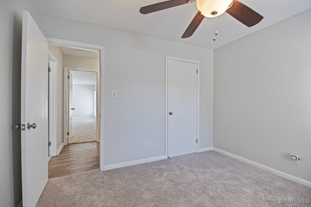 unfurnished bedroom with a closet, light colored carpet, and ceiling fan