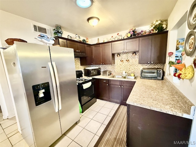 kitchen featuring dark brown cabinets, backsplash, light tile patterned floors, and black appliances