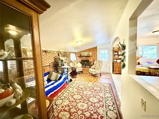 interior space featuring a healthy amount of sunlight, light tile patterned flooring, brick wall, and lofted ceiling