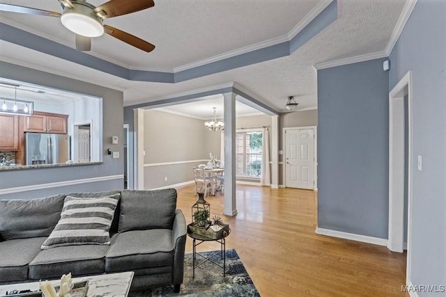 living room featuring a textured ceiling, light hardwood / wood-style floors, a raised ceiling, and crown molding