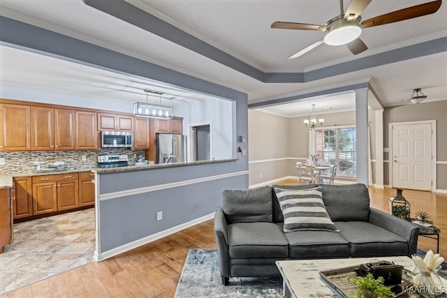 living room featuring ceiling fan with notable chandelier, light hardwood / wood-style floors, a raised ceiling, and crown molding