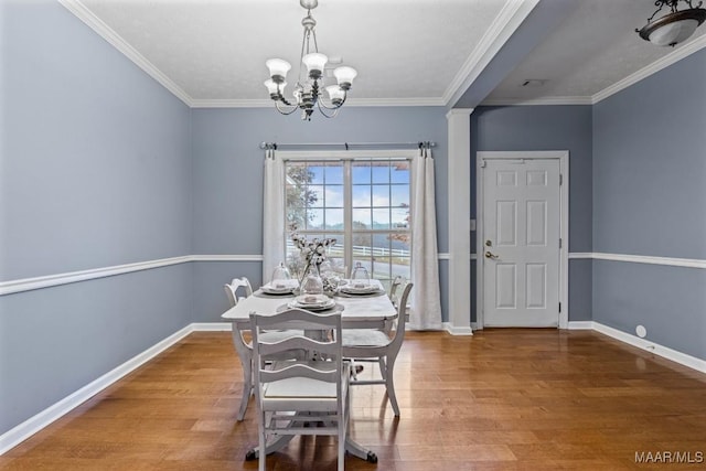 dining room with wood-type flooring, crown molding, and a notable chandelier