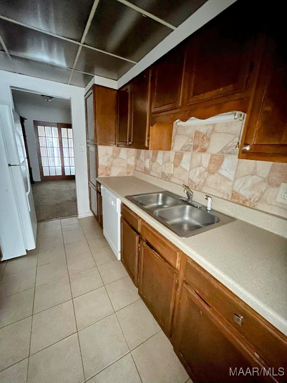 kitchen with decorative backsplash, light tile patterned flooring, white appliances, and sink