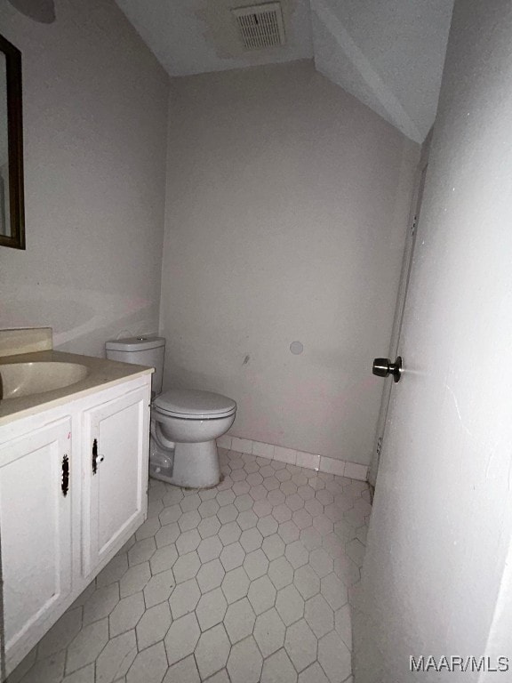 bathroom with toilet, vanity, and tile patterned floors