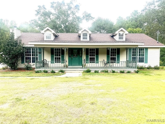 new england style home with covered porch, a front lawn, and a shingled roof