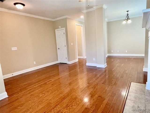 spare room with an inviting chandelier, wood-type flooring, and ornamental molding