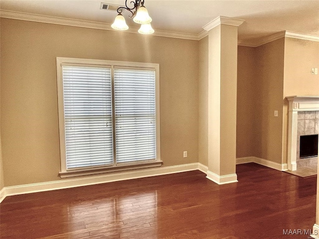 interior space featuring a tiled fireplace, a chandelier, dark wood-type flooring, and ornamental molding