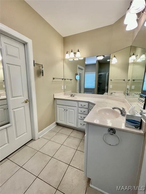 bathroom with tile patterned flooring, vanity, a shower with door, and vaulted ceiling