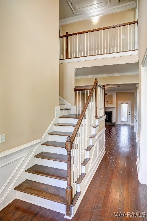 stairway featuring a towering ceiling, hardwood / wood-style flooring, and ornamental molding