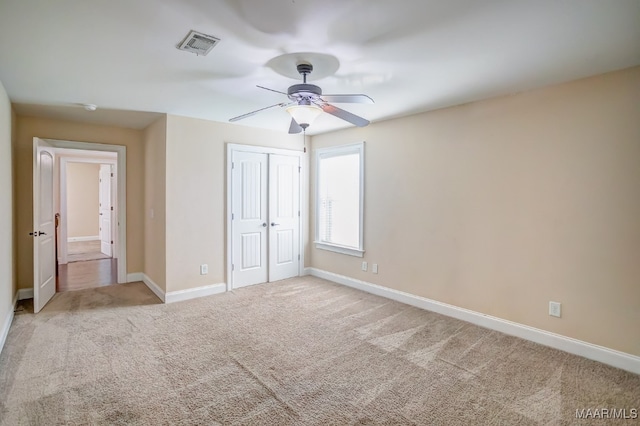 unfurnished bedroom featuring ceiling fan, a closet, and light colored carpet