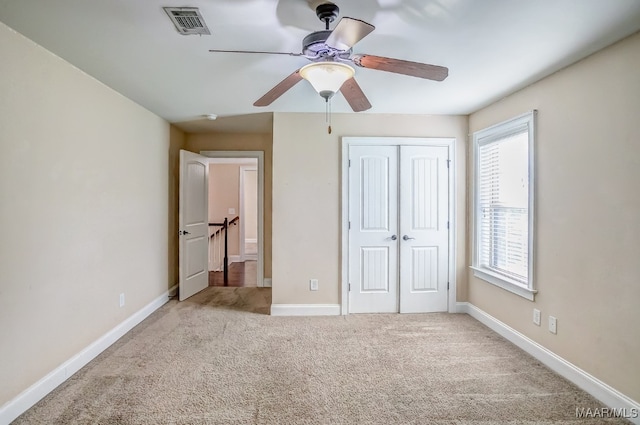 unfurnished bedroom with ceiling fan, a closet, and light carpet