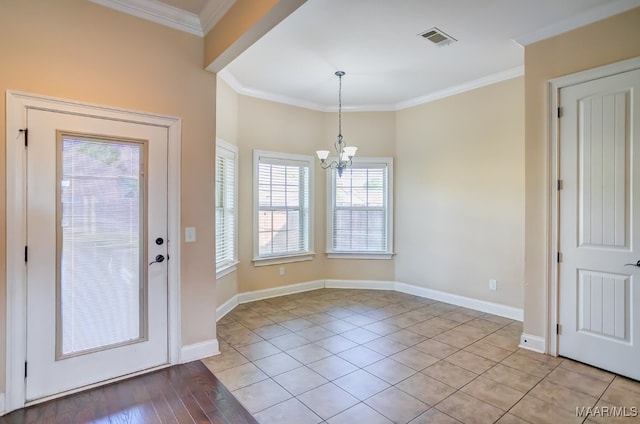 tiled foyer featuring crown molding, a wealth of natural light, and a chandelier