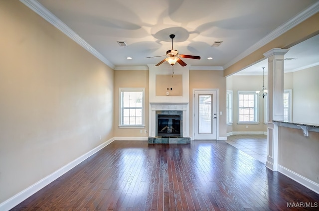 unfurnished living room with dark hardwood / wood-style flooring, decorative columns, ceiling fan with notable chandelier, crown molding, and a fireplace