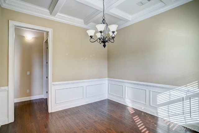 spare room featuring beam ceiling, dark hardwood / wood-style flooring, ornamental molding, and an inviting chandelier